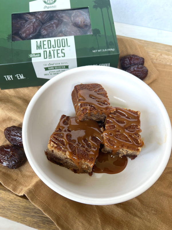 Picture of Gluten Free Sticky Date Pudding on a mustard yellow napkin with a box of Coachella's Best Organic Dates and Dates around 