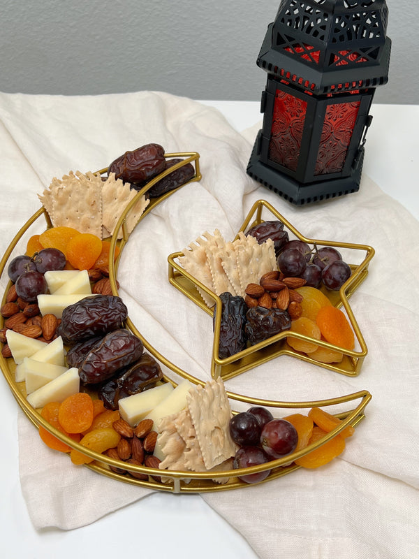 A photo of a crescent moon and star platter filled with cheese, crackers, dried apricots, grapes, almonds, and Coachella''s Best Organic Medjool Dates on cream napkin. 